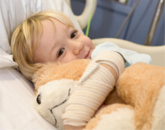 Child in recovery clutching a teddy bear